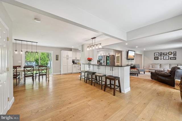 kitchen featuring white cabinetry, light wood finished floors, stainless steel appliances, and a kitchen bar