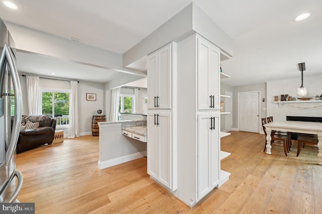 interior space with open shelves, light wood-type flooring, white cabinets, and open floor plan