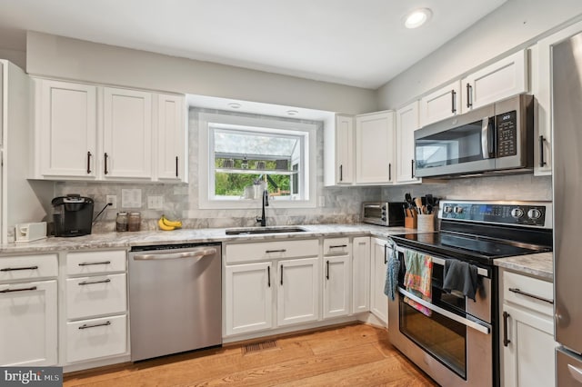 kitchen featuring white cabinetry, appliances with stainless steel finishes, tasteful backsplash, and a sink