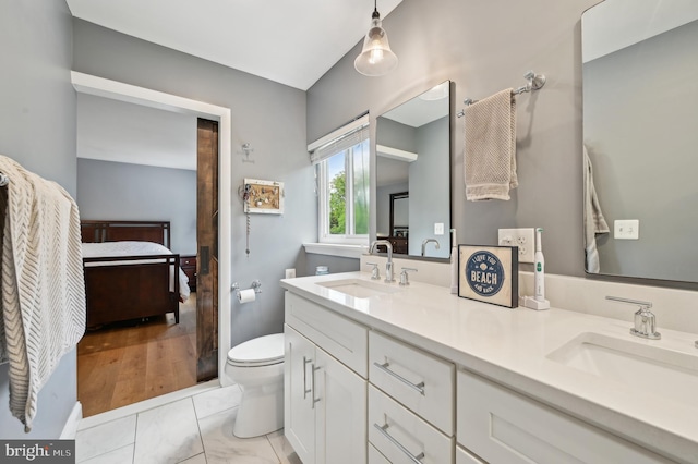 ensuite bathroom featuring double vanity, ensuite bath, toilet, and a sink