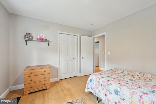 bedroom with baseboards, a closet, and light wood-style floors