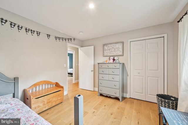 bedroom with light wood finished floors, a closet, and baseboards