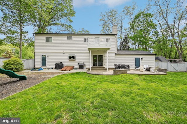 rear view of property with a balcony, a yard, a patio, and a fenced backyard