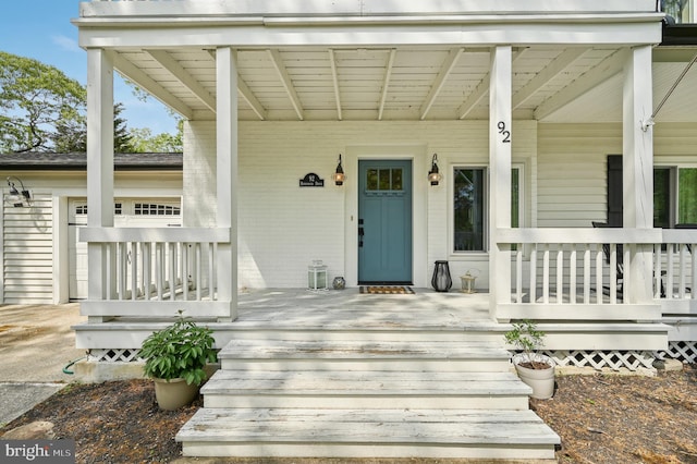 view of exterior entry featuring a porch and brick siding