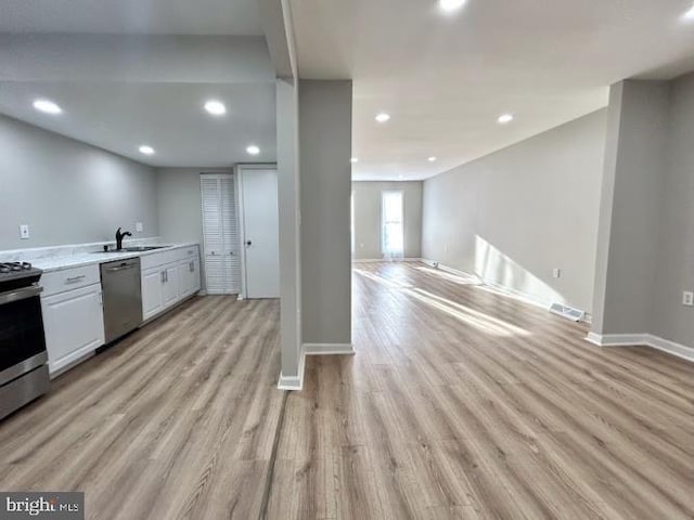 kitchen featuring appliances with stainless steel finishes, recessed lighting, a sink, light countertops, and light wood-type flooring