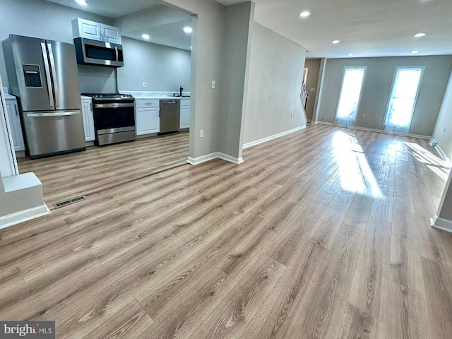 kitchen featuring light wood-style flooring, stainless steel appliances, visible vents, baseboards, and light countertops