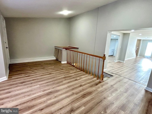 interior space featuring baseboards, an upstairs landing, and wood finished floors