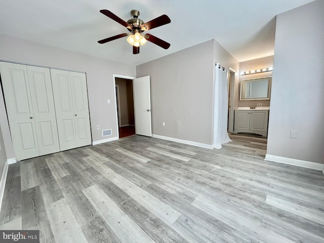 unfurnished bedroom featuring baseboards, ensuite bath, light wood-style flooring, and visible vents