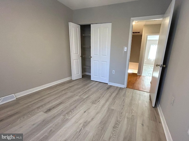 unfurnished bedroom with baseboards, light wood finished floors, and visible vents