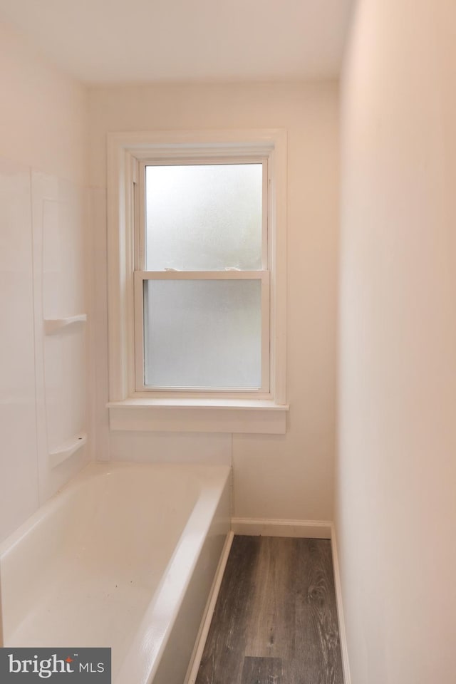 bathroom featuring a tub to relax in, baseboards, and wood finished floors