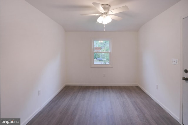 spare room featuring baseboards, a ceiling fan, and dark wood-style flooring