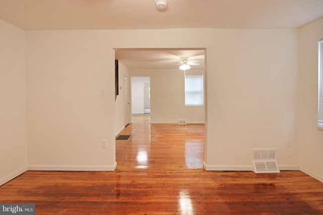 empty room with baseboards, ceiling fan, hardwood / wood-style flooring, and visible vents