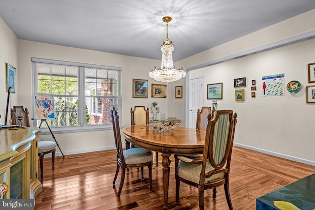 dining area with baseboards, wood finished floors, a notable chandelier, and visible vents