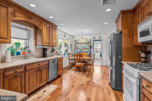 kitchen featuring a sink, decorative backsplash, brown cabinets, and stainless steel appliances
