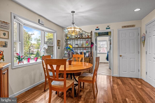 dining area with light wood-style floors, baseboards, and a notable chandelier