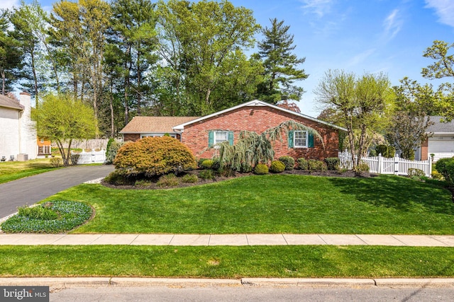 single story home featuring brick siding, fence, and a front lawn