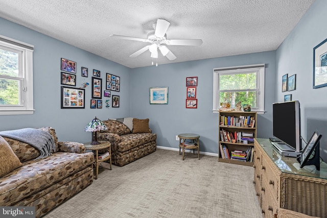 carpeted living room featuring baseboards, a ceiling fan, and a textured ceiling