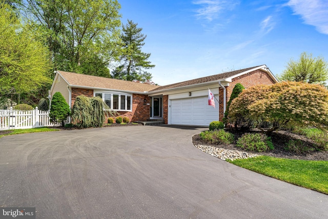 ranch-style home with brick siding, a garage, fence, and driveway