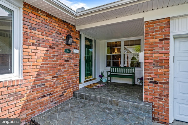 doorway to property with brick siding and covered porch