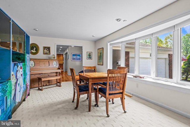 dining space featuring baseboards, plenty of natural light, and light carpet