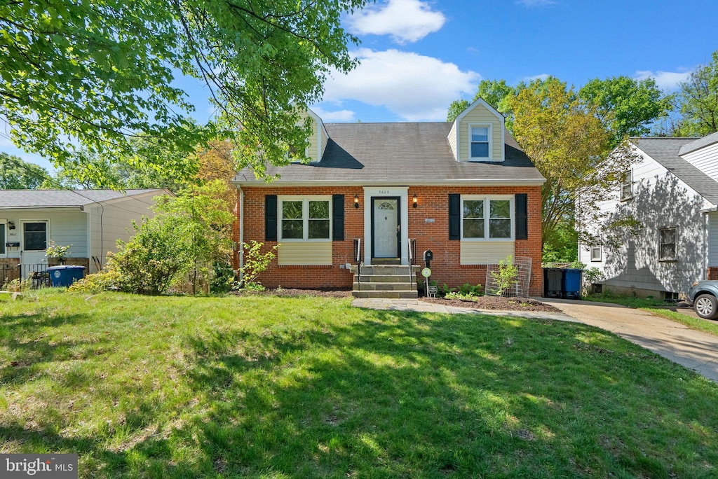 cape cod house with concrete driveway, brick siding, and a front yard
