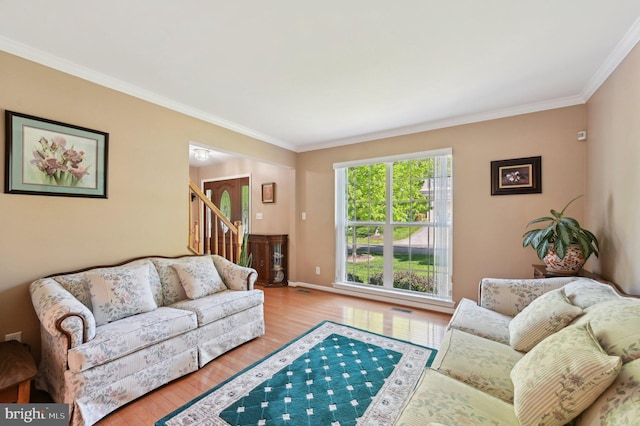 living area featuring stairway, ornamental molding, visible vents, and wood finished floors