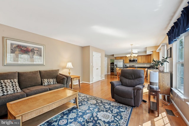 living room with light wood finished floors, baseboards, and a notable chandelier