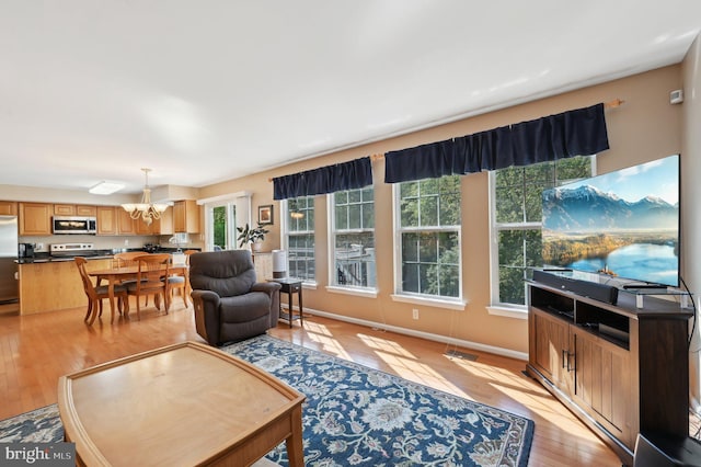 living area featuring visible vents, light wood-style flooring, and a chandelier
