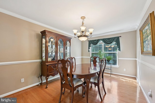 dining room with light wood-type flooring, baseboards, ornamental molding, and a notable chandelier