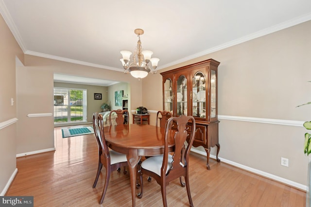 dining area featuring crown molding, baseboards, light wood-style flooring, and a chandelier
