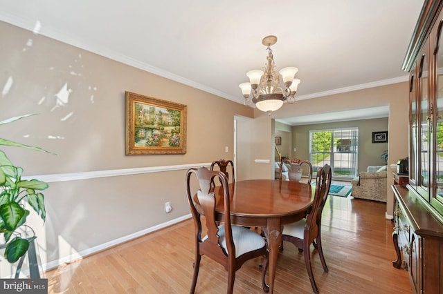 dining area with an inviting chandelier, light wood-style flooring, crown molding, and baseboards