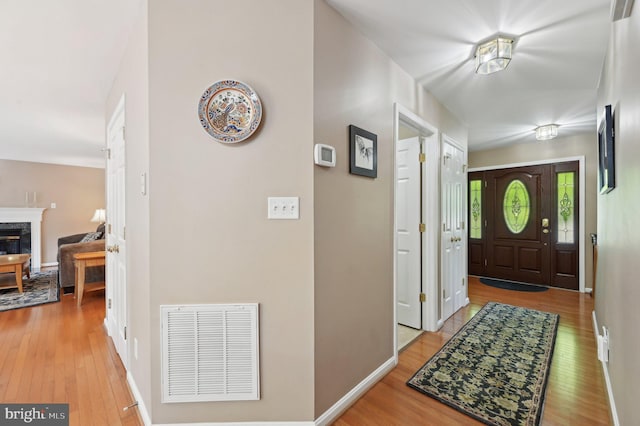 foyer entrance with visible vents, baseboards, a premium fireplace, and hardwood / wood-style floors