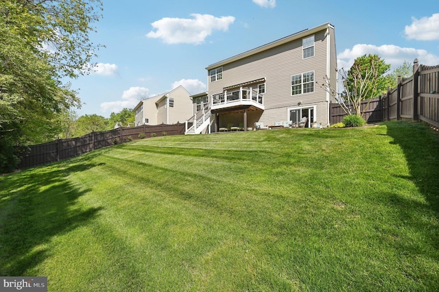 back of property featuring a yard, a deck, a fenced backyard, and stairs