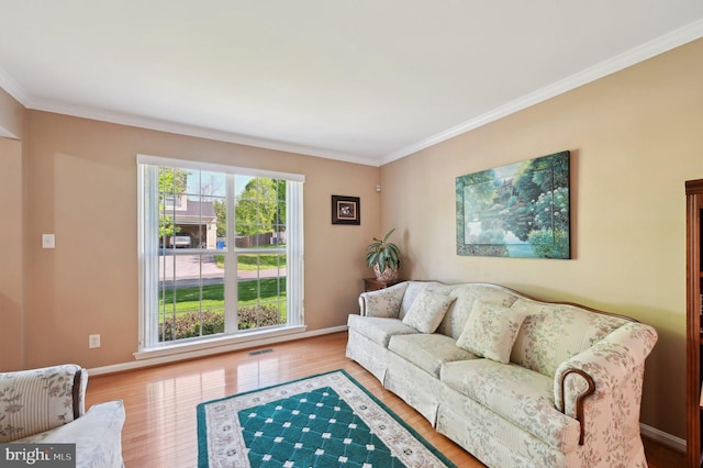 living area with crown molding, baseboards, wood finished floors, and visible vents