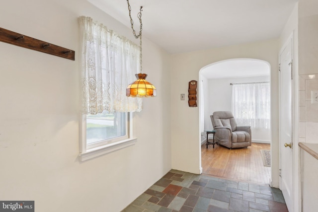 hallway with arched walkways and stone finish flooring