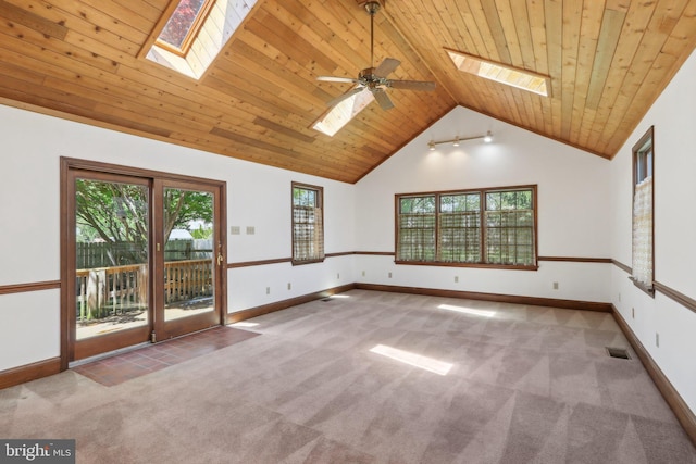 carpeted empty room featuring vaulted ceiling with skylight, a ceiling fan, baseboards, visible vents, and wood ceiling