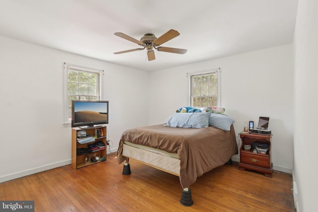 bedroom with baseboards, a ceiling fan, multiple windows, and hardwood / wood-style flooring