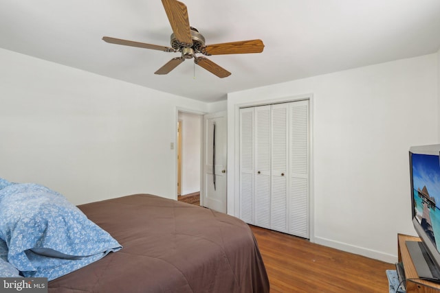 bedroom with a ceiling fan, baseboards, wood finished floors, and a closet