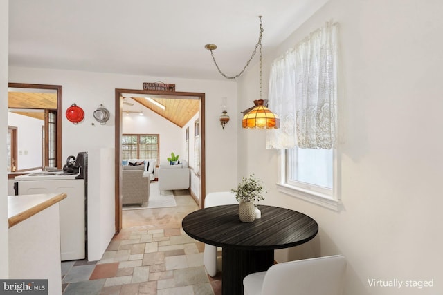 hall featuring lofted ceiling and stone finish floor