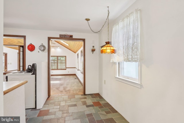 hallway featuring stone finish floor and lofted ceiling
