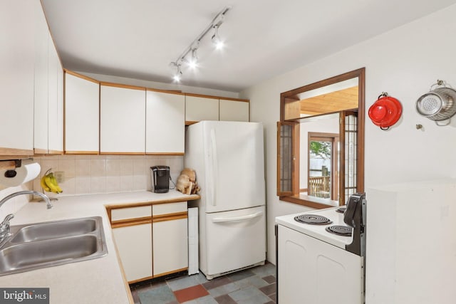 kitchen featuring backsplash, rail lighting, a sink, light countertops, and white appliances