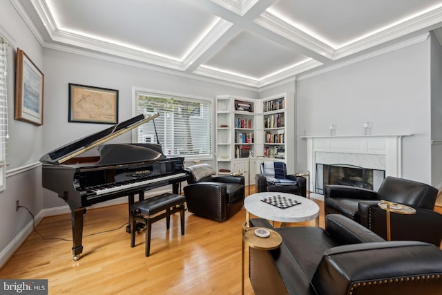 sitting room featuring light wood-style flooring, coffered ceiling, a premium fireplace, crown molding, and built in shelves