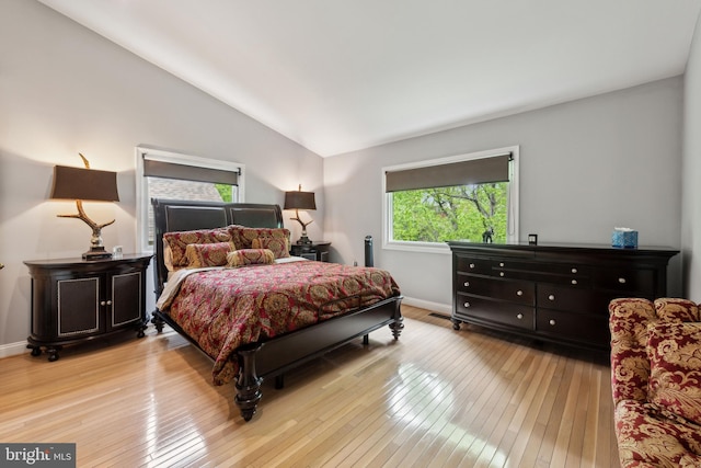 bedroom featuring light wood finished floors, lofted ceiling, and baseboards