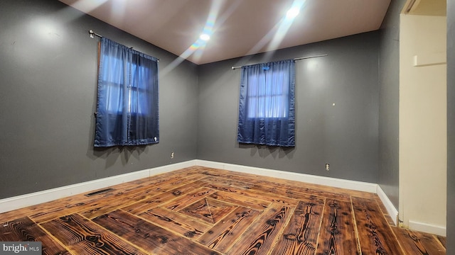 unfurnished room featuring visible vents, vaulted ceiling, and baseboards