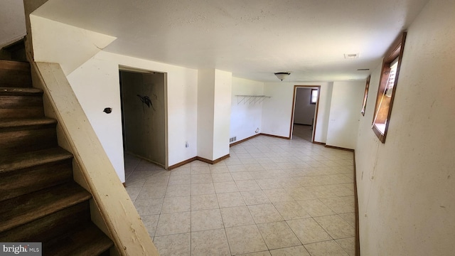 interior space with light tile patterned floors, stairs, visible vents, and baseboards