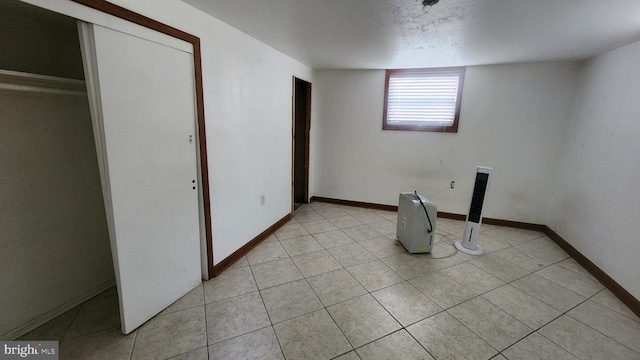 interior space featuring light tile patterned floors, laundry area, and baseboards