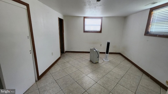 interior space featuring baseboards, visible vents, and light tile patterned floors