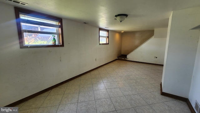 below grade area featuring light tile patterned flooring, visible vents, and baseboards