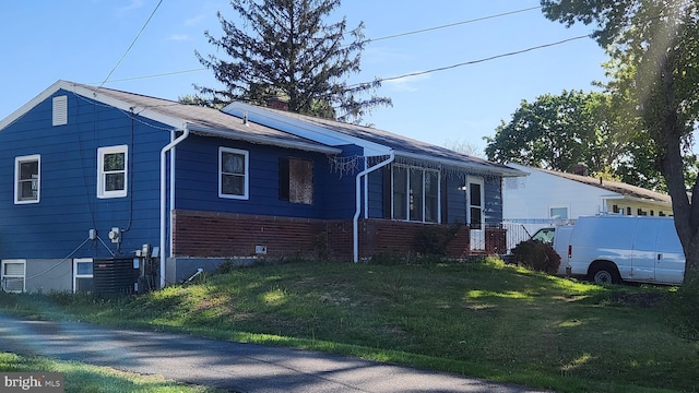 view of property exterior featuring a chimney, brick siding, and a lawn
