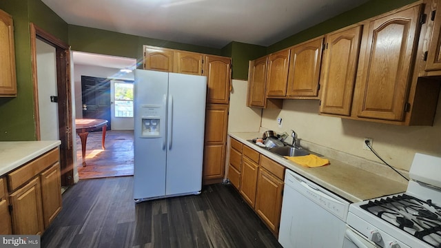 kitchen with white appliances, light countertops, dark wood finished floors, and a sink
